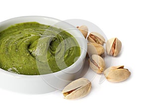 Bowl of creamy pistachio butter and nuts on white background, closeup photo