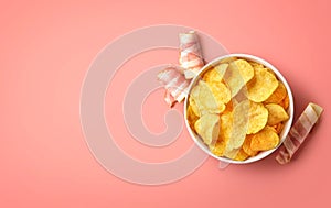 Bowl of crispy potato chips or crisps with bacon flavor on pink background