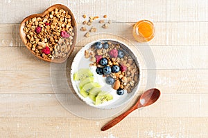 Bowl of crunchy honey granola with blueberries, kiwi and greek yogurt