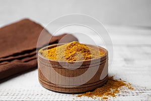 Bowl with curry powder on white wooden table, closeup