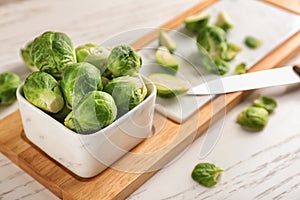 Bowl and cutting board with fresh brussels sprouts on table