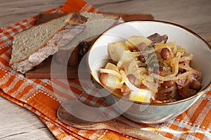 A bowl of delcious homemade stew with potato, turnip, sausages, celery, and onion. Served with fresh bread. European kitchen