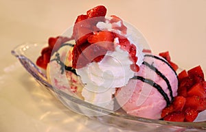 Bowl of delectable ice cream strawberry sundae topped with fresh berries and whipped cream