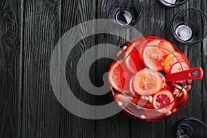 Bowl of delicious aromatic punch drink, ladle and empty glasses on black wooden table, flat lay. Space for text