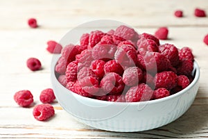 Bowl of delicious fresh ripe raspberries on white wooden table, closeup