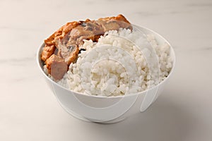 Bowl of delicious rice with meat and mushrooms on white marble table