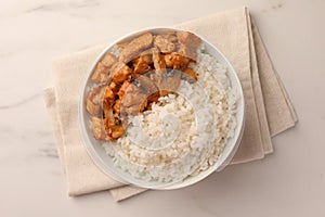 Bowl of delicious rice with meat and mushrooms on white marble table, top view