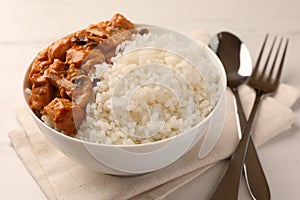 Bowl of delicious rice with meat and mushrooms on white table, closeup