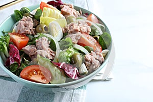 Bowl of delicious salad with canned tuna and vegetables on white table, closeup. Space for text