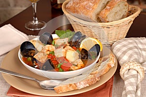 Bowl of delicious seafood soup with wine and rustic bread