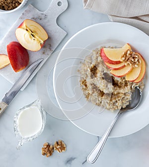 Bowl of steel cut oats and brown sugar topped with apple slices with milk on the side ready for pouring. photo