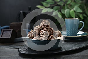 Bowl of delicious sweet chocolate candies on black wooden table