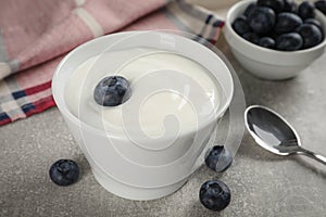 Bowl with delicious yogurt and blueberries on grey table, closeup