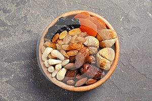 Bowl with different dried fruits and nuts on table