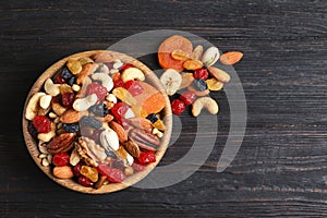 Bowl with different dried fruits and nuts on table, top view