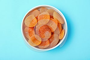 Bowl with dried apricots on color background, top view.