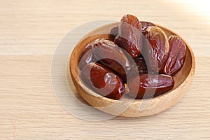 Bowl of dried dates isolated on wooden background