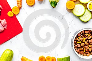 Bowl of dry dogfood, carrot, courgette, meat table background to photo