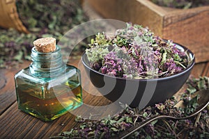 Bowl of dry Origanum vulgare or wild marjoram flowers. Bottle of essential oil or infusion photo