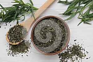Bowl of dry tarragon, spoon and fresh leaves on white wooden table, flat lay