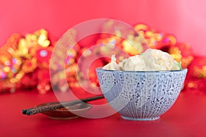 A bowl of dumplings and a pair of chopsticks on a red background