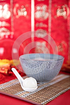 A bowl of dumplings on a red background and a dumpling in a small spoon. The Chinese characters in the picture mean `happiness`