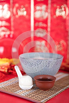 A bowl of dumplings on a red background and a dumpling in a small spoon. The Chinese characters in the picture mean `happiness`