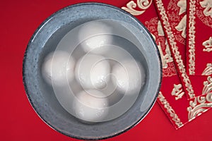 A bowl of dumplings and red envelopes on a red background.The Chinese meaning in the picture is `happiness` and `good luck`