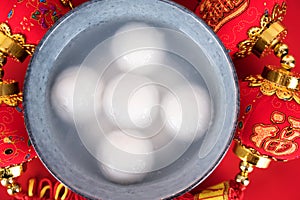 A bowl of dumplings and red envelopes on a red background.The Chinese meaning in the picture is `happiness` and `good luck`