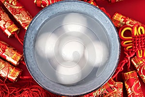 A bowl of dumplings and red envelopes on a red background.The Chinese meaning in the picture is `happiness` and `good luck`