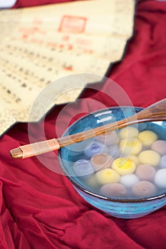 A bowl of dumplings and traditional folding fans on a red cloth background