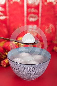 A bowl of dumplings or Yuanxiao on a festive red background with a spoon. The Chinese characters in the picture mean `happiness` a