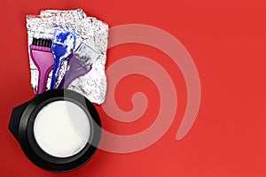 Bowl with dye and hair coloring kit on a red background