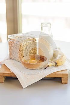 Bowl with egg and banana with cereals in glass jar with milk bottle on table, ingredients for cocking pancakes