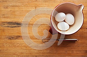 Bowl with eggs and whisk on butcher
