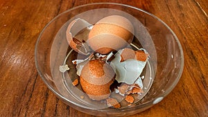 A bowl of eggshells sits on a wooden table.