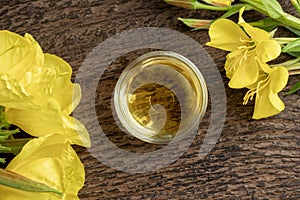 A bowl of evening primrose oil with blooming evening primrose plant