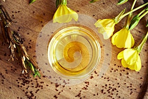 A bowl of evening primrose oil with evening primrose seeds and flowers