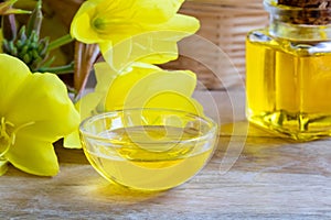 A bowl of evening primrose oil with fresh blooming evening primrose