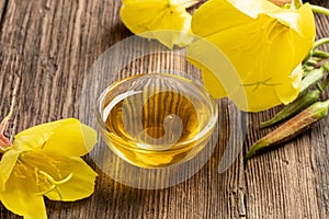 A bowl of evening primrose oil with fresh blooming evening primrose