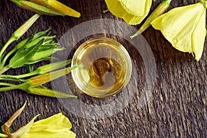 A bowl of evening primrose oil with fresh blooming evening primrose plant