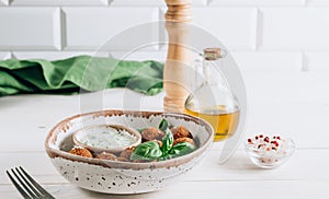 Bowl of falafel with tzatziki sauce on a white wooden table