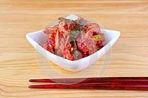 Bowl of Famous Korean Dish Kimchi with a Pair of Chopsticks on Wooden Table