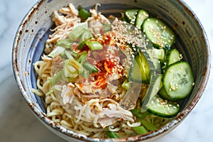 A bowl filled with cold sesame noodles topped with slices of cucumber and sprinkled with sesame seeds, A refreshing bowl of cold