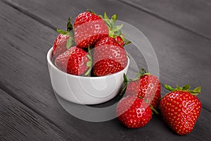 Bowl filled with fresh ripe red strawberries on wooden