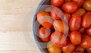 Bowl filled with grape tomatoes on a wood table