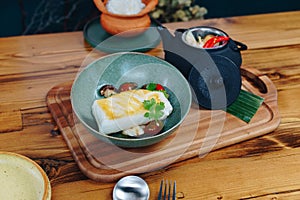 A bowl of fish with a side of vegetables and a teapot