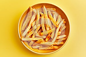 Bowl of french fried potatoes over yellow background