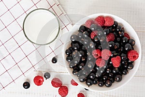 Bowl with fresh berries and glass of milk