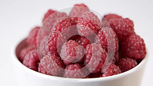 A bowl of fresh berries is on the table.Raspberries in a plate.